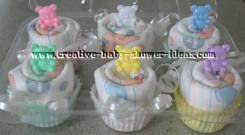 6 baby diaper cupcakes with colorful bear picks in a cupcake tray