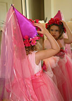 girl in princess costume and hat looking in mirror