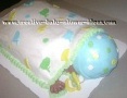 sleeping baby on its belly cake covered with white blanket and blue hat