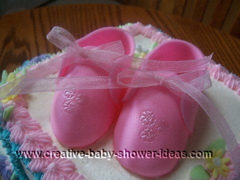 closeup of pink booties on blocks cake